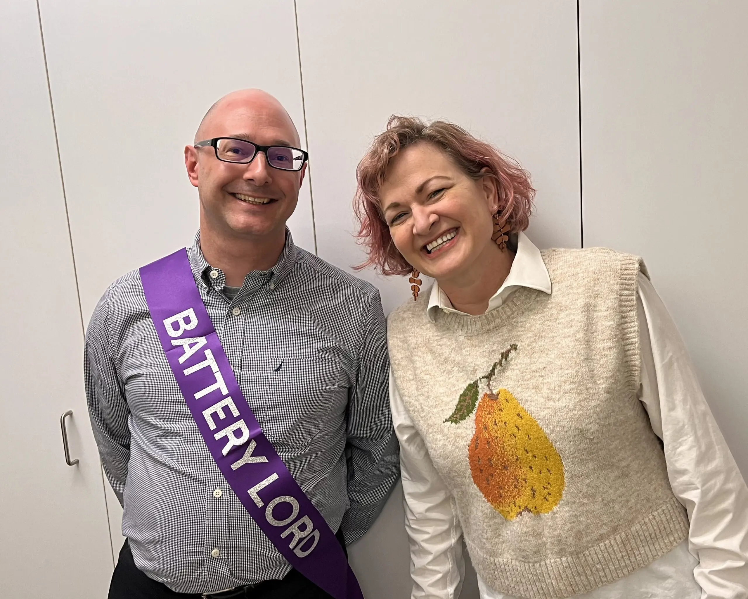 Chris Silkowski, wearing a "BATTERY LORD" sash, and a companion smiling for a picture