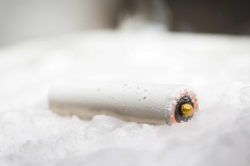 a single cylindrical battery lying horizontally on a bed of white ice