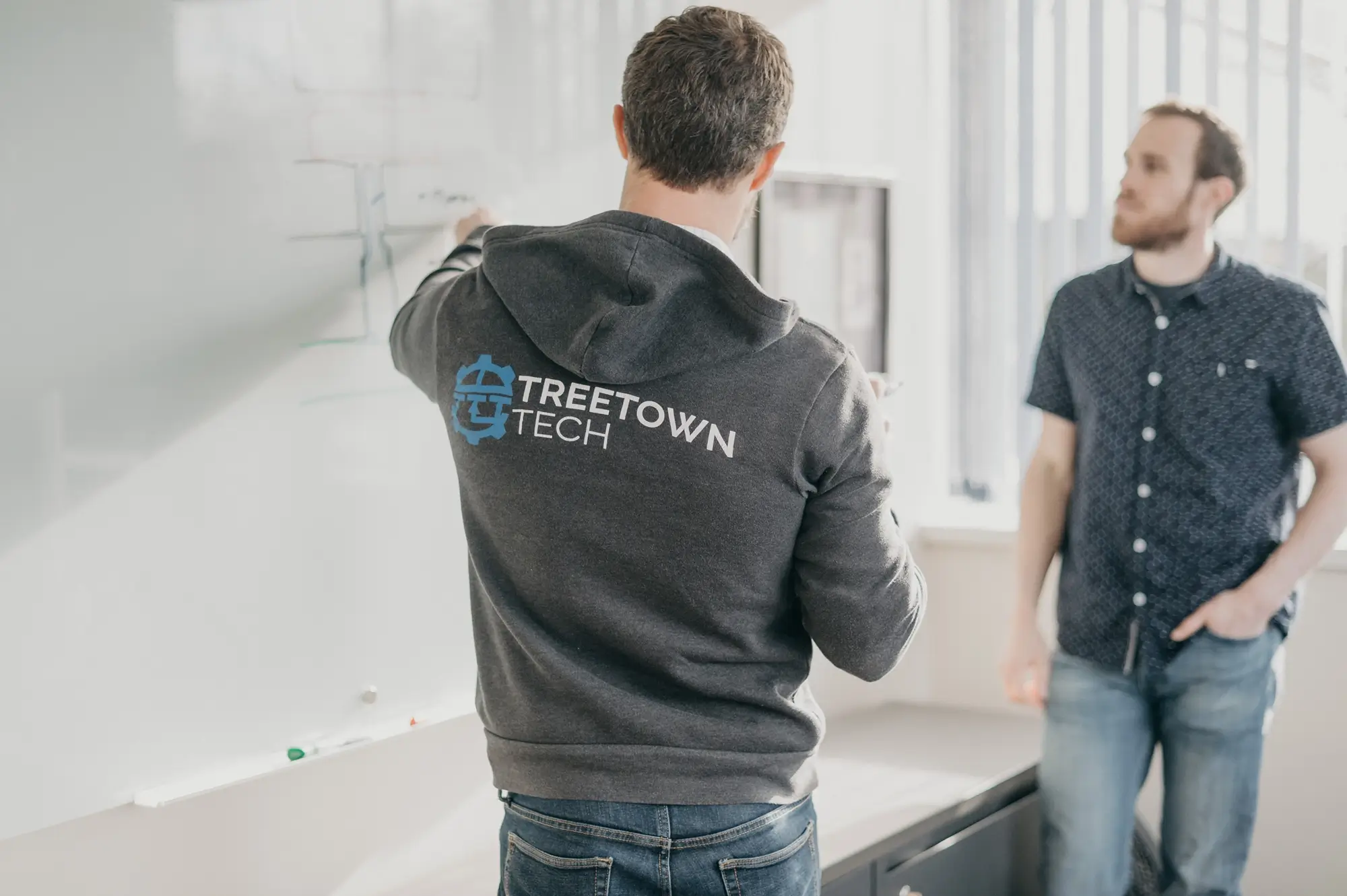 Treetown Tech employees discussing project and writing on a white board