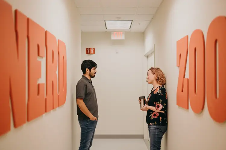 Treetown Tech employees having a conversation in a hallway with the words 