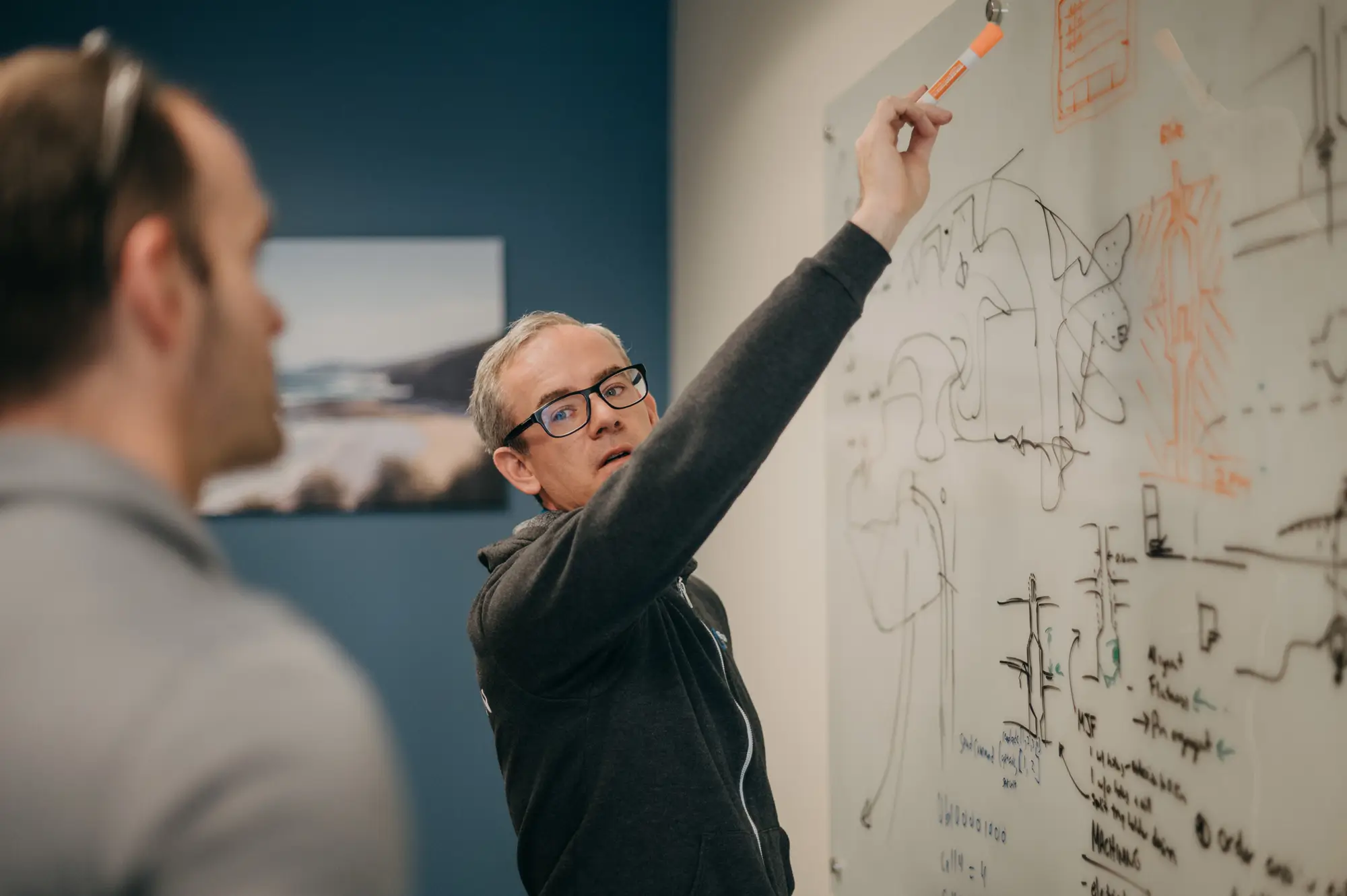 Treetown Tech employees discussing project and writing on a white board