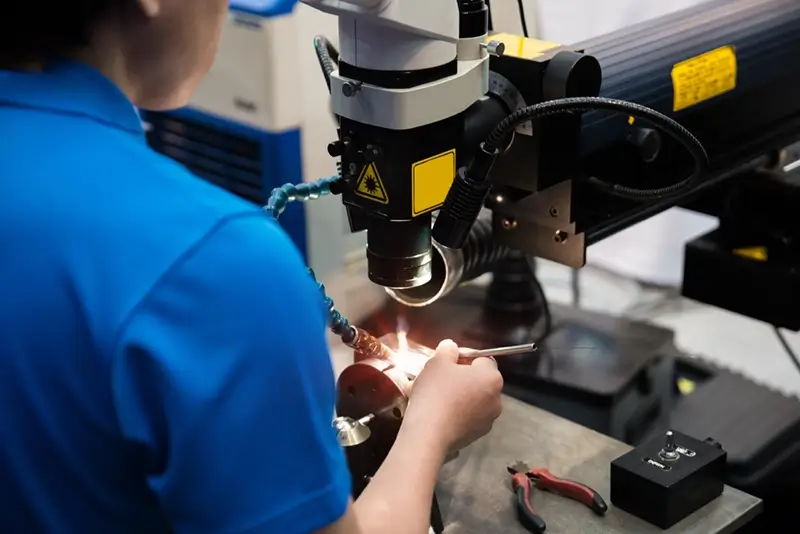 Worker welding repair mold and die part by Laser welding machine in factory.